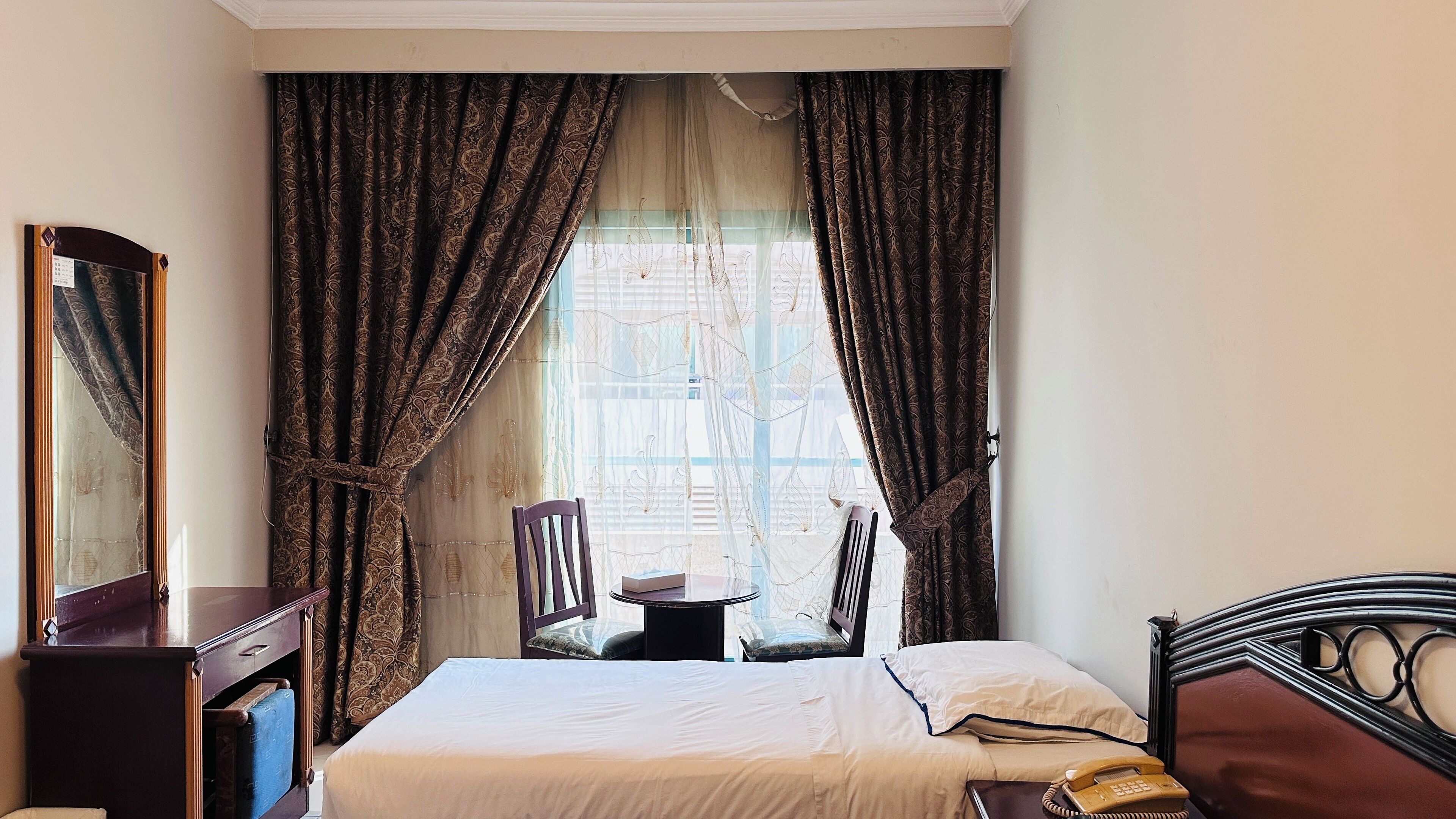 Une chambre d’hôtel équipée d’un lit, d’un bureau, d’une chaise et d’un téléphone.