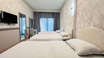 A hotel room with two beds, a TV mounted on the wall, a mirror, and a window with curtains.