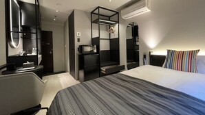 Ett modernt hotellrum med en säng, ett skrivbord, en spegel och en garderob.