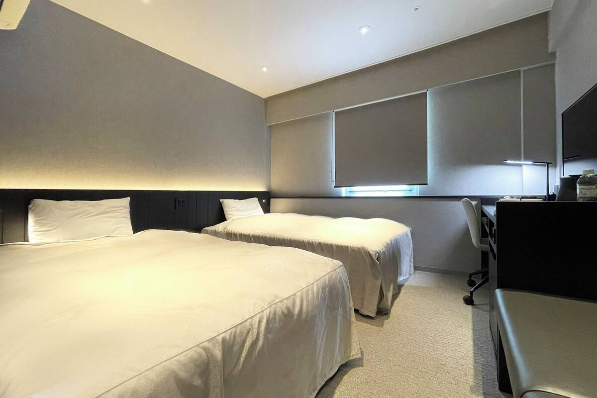 A hotel room with two beds, a desk, and a chair.