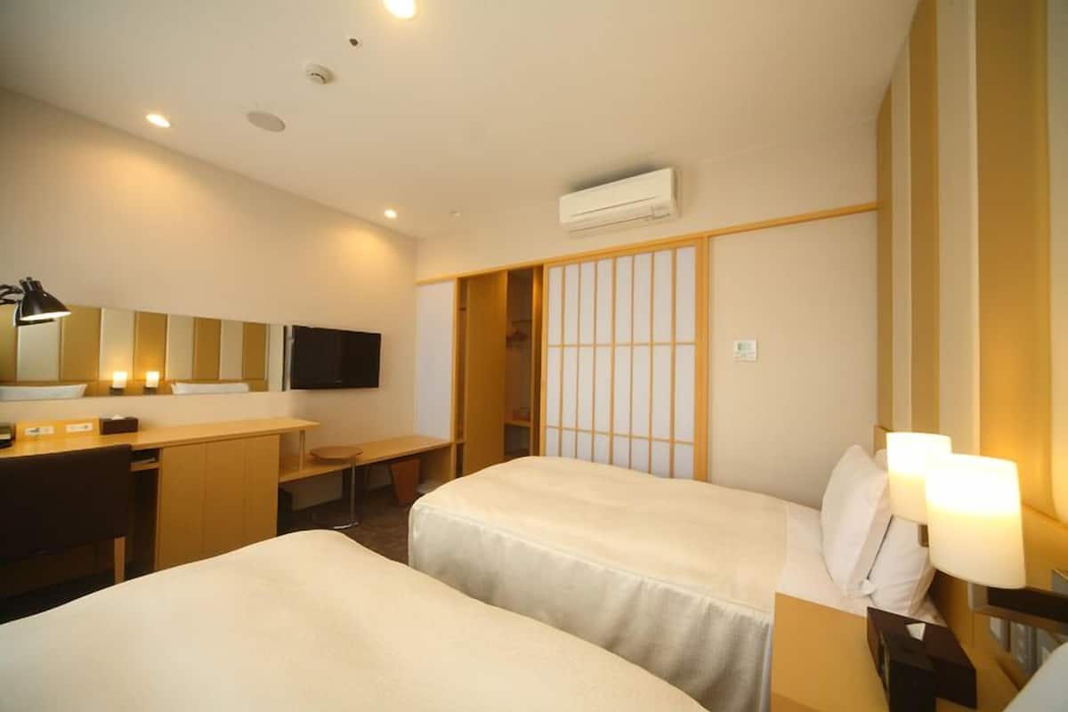 A hotel room with two beds, a desk, a chair, a TV, and a sliding door.
