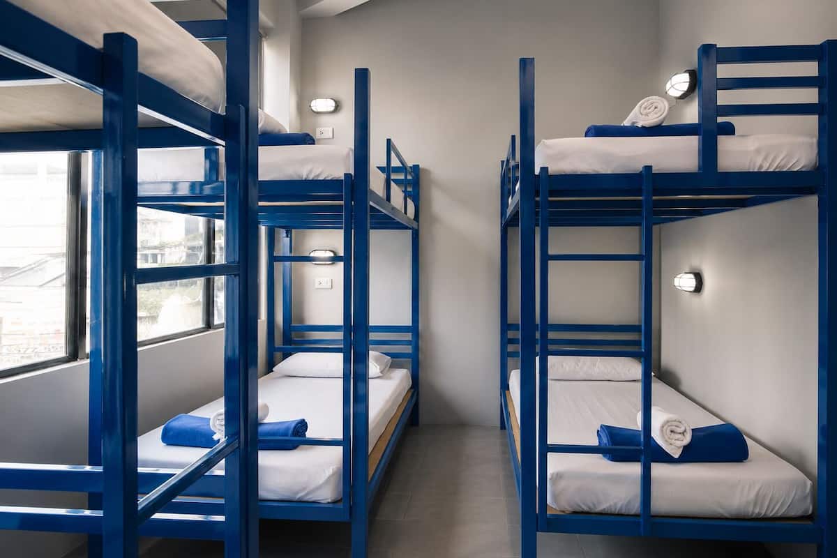 A bunk bed room with a window, a wall-mounted light, and a power outlet.
