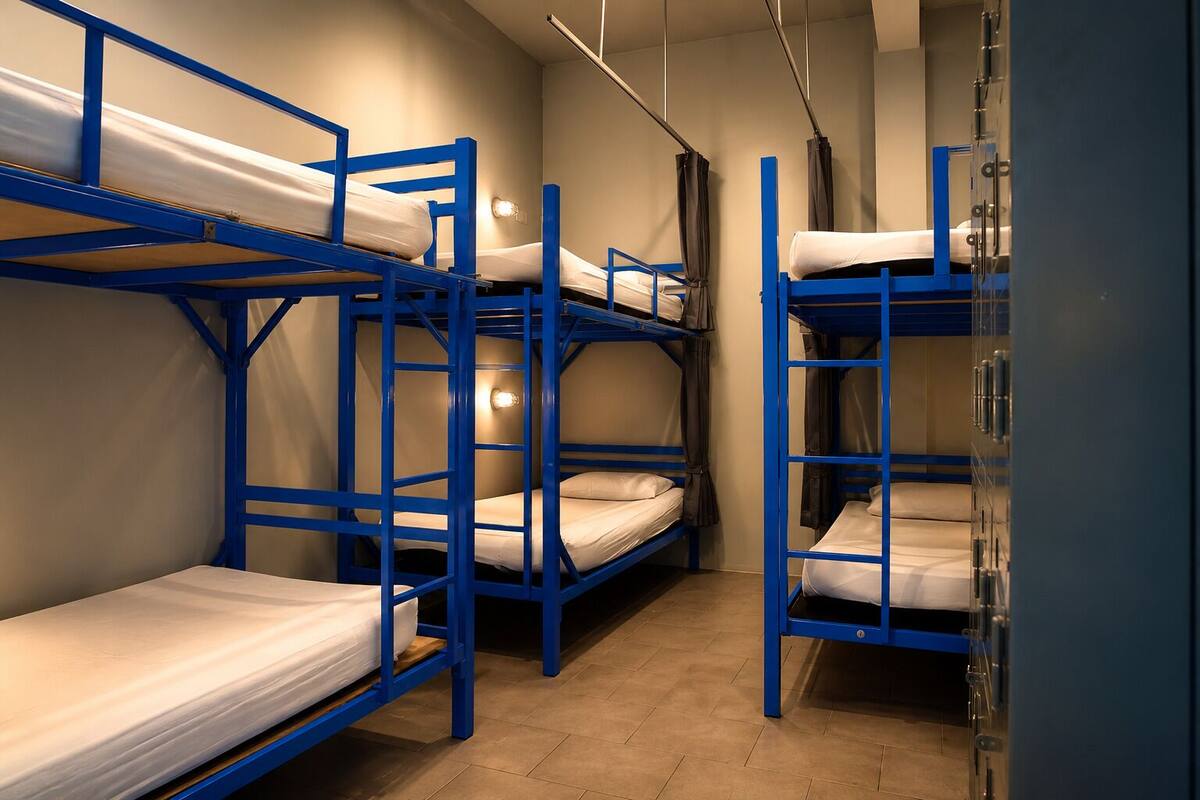 Bunk beds with a blue frame, a light fixture on the wall, and a tiled floor.