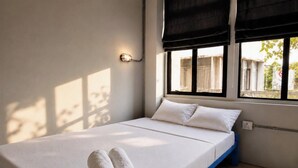 A single bed with white bedding, a window with a view of buildings, and a wall-mounted light fixture. - Loftel Station Hostel (Bangkok)