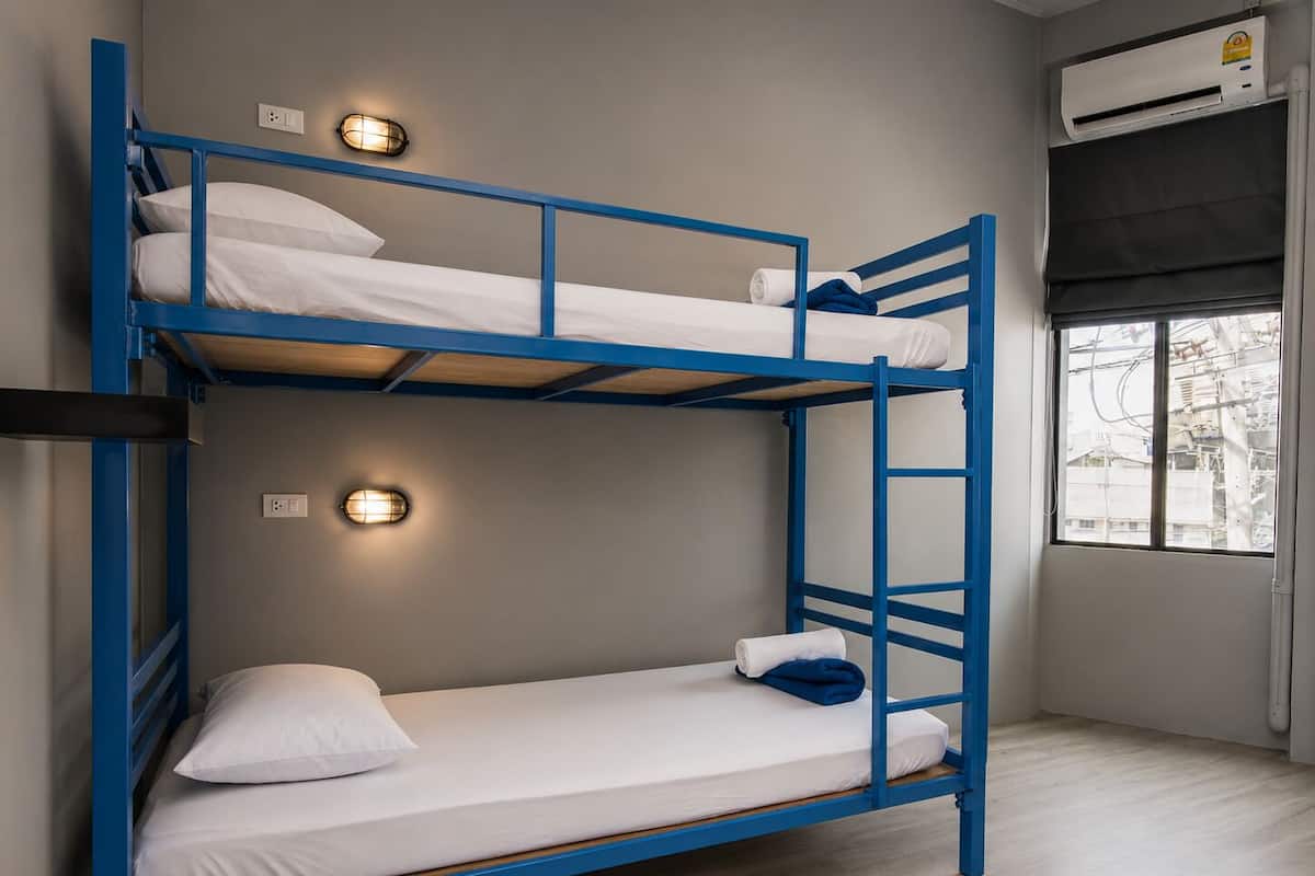 A bunk bed room with two beds, a window with a view, and an air conditioning unit.