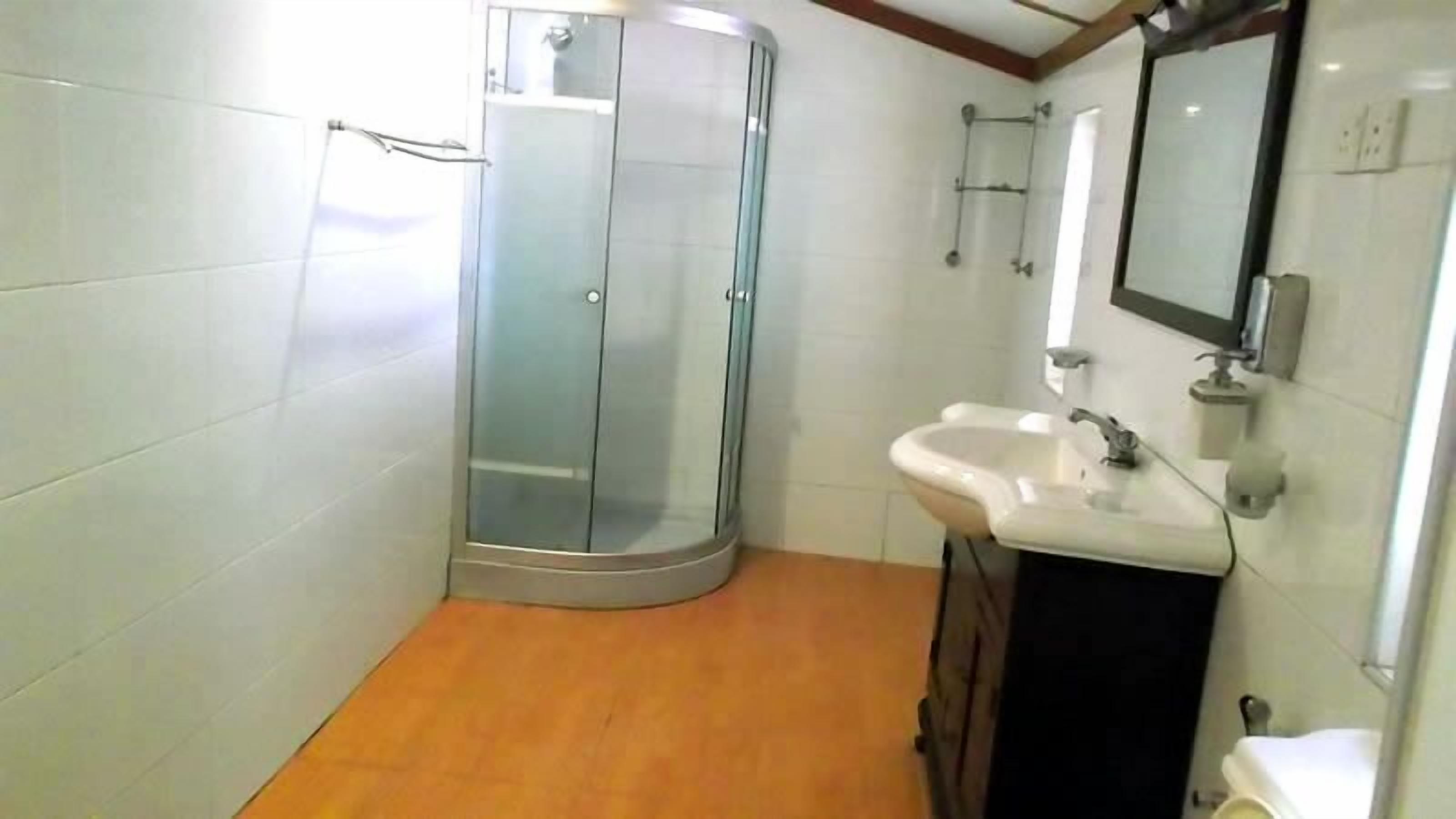 A bathroom with a glass shower enclosure, a sink, and a mirror.