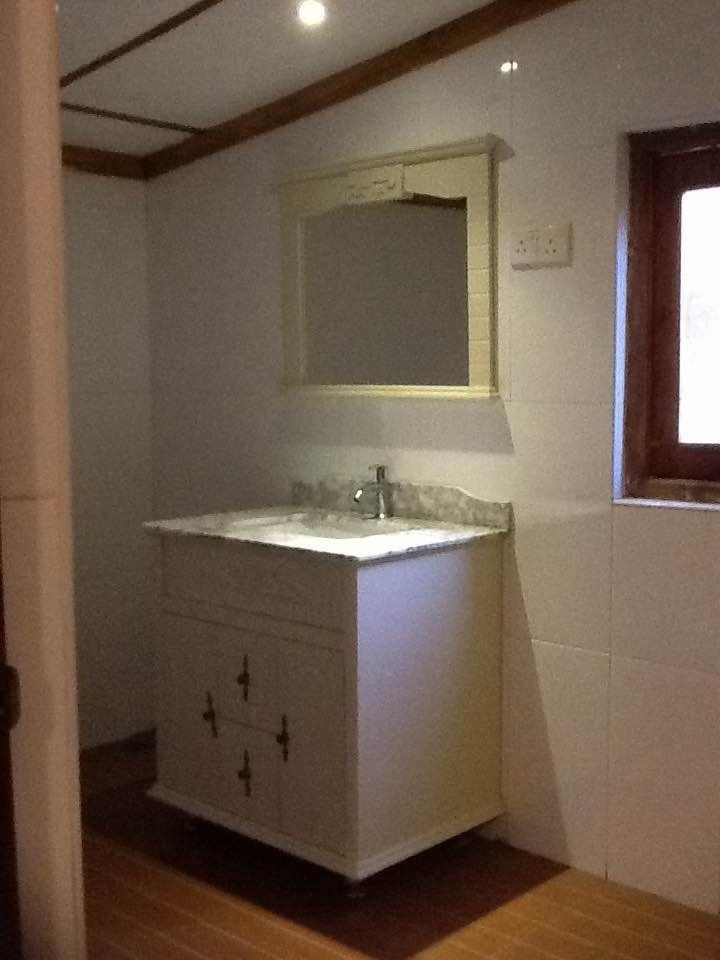 Un baño con tocador blanco, un espejo y una ventana.