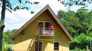 A two-story yellow house with a balcony on the upper floor.