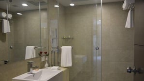 Ein modernes Badezimmer mit einer Duschkabine, einem weißen Waschbecken und einem Spiegel.