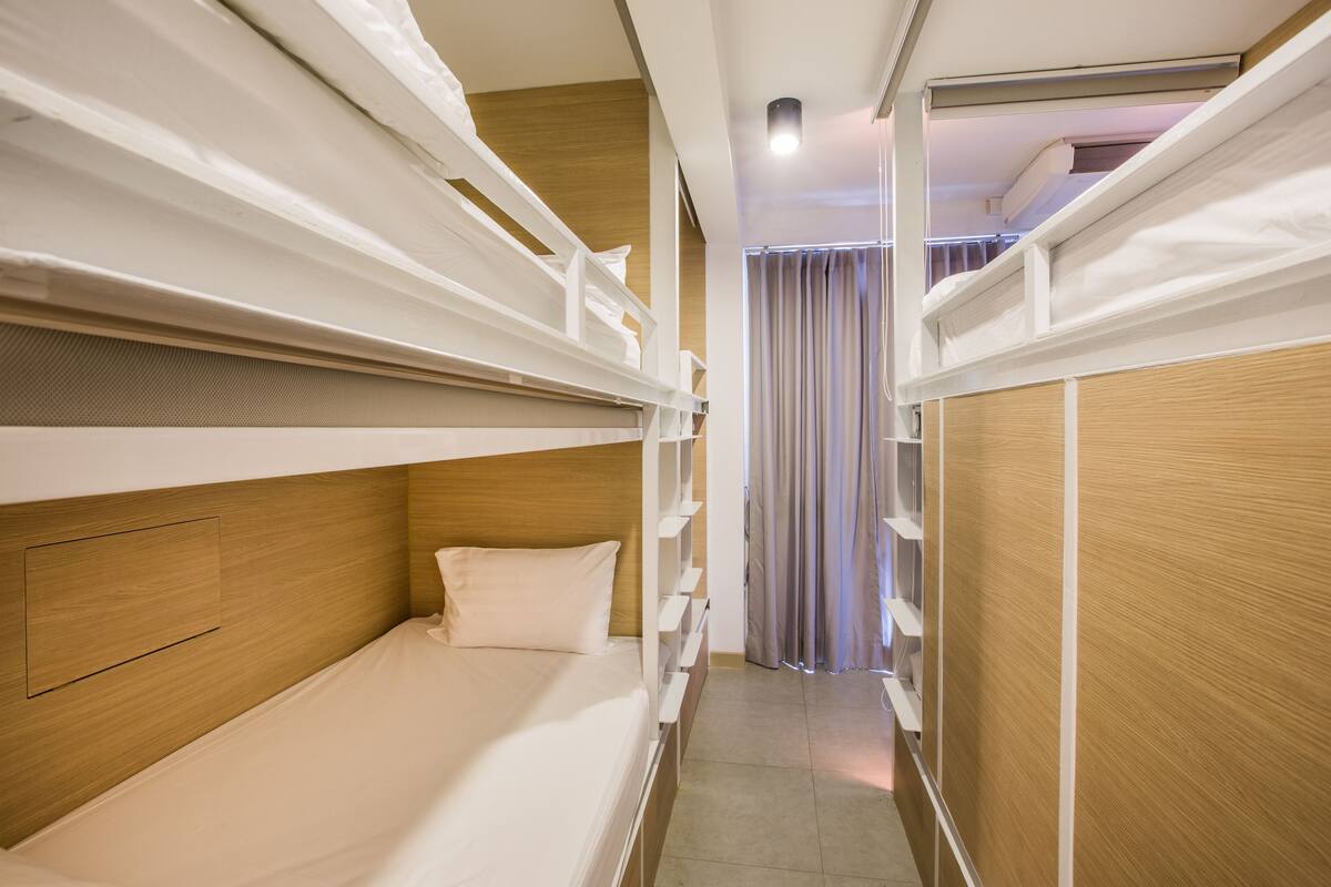 A bunk bed room with a wooden headboard, a bedside table, and a curtain.