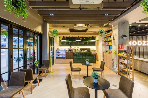 A modern cafe interior with seating, a counter, and a view of the street. - Snoozz Hotel - Hostel (Krabi)