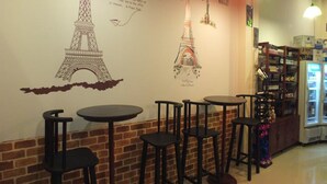 A café interior with a mural of the Eiffel Tower, brick walls, and a beverage refrigerator. - Avalon Residence (Savannakhet)