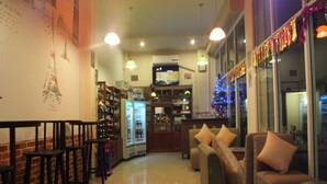 A cozy restaurant with wooden tables and chairs, a bar area, and a seating area with sofas. - Avalon Residence (Savannakhet)