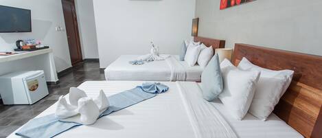 A hotel room with two beds, a desk, a television, and an air conditioning unit.