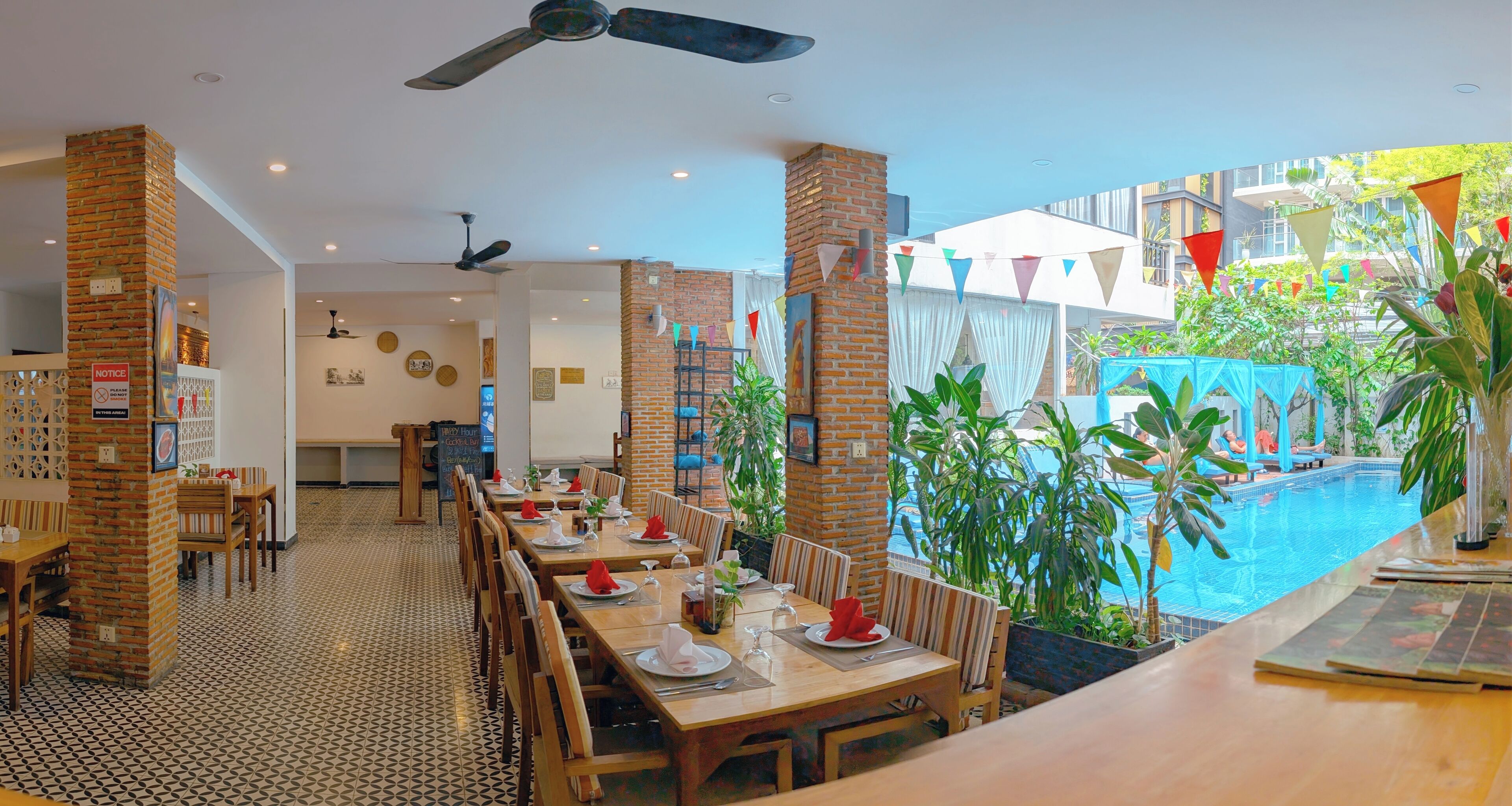 Un restaurant avec vue sur la piscine, des piliers en briques et un sol carrelé.