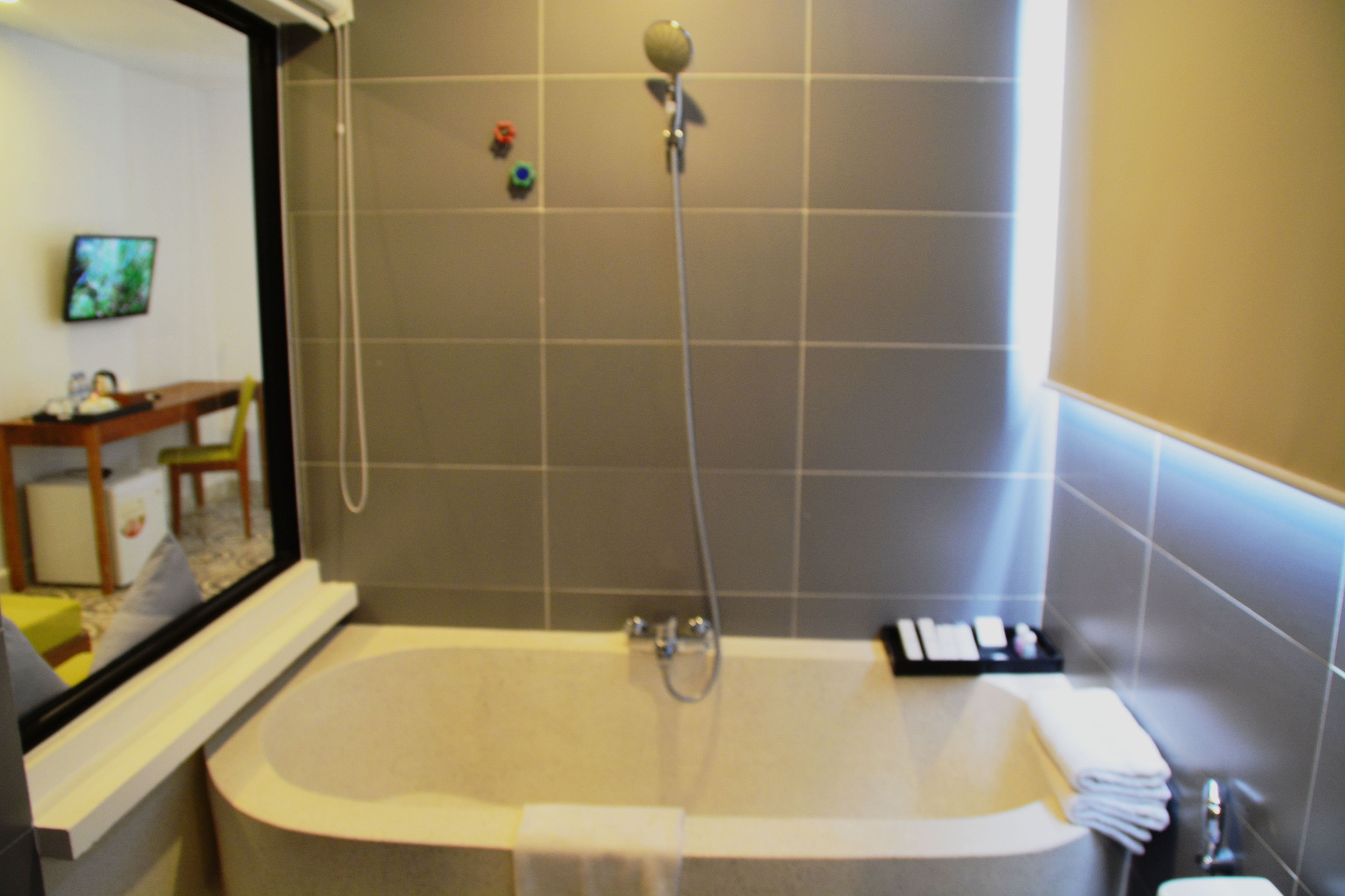 A bathroom with a bathtub, a showerhead, and a toilet.