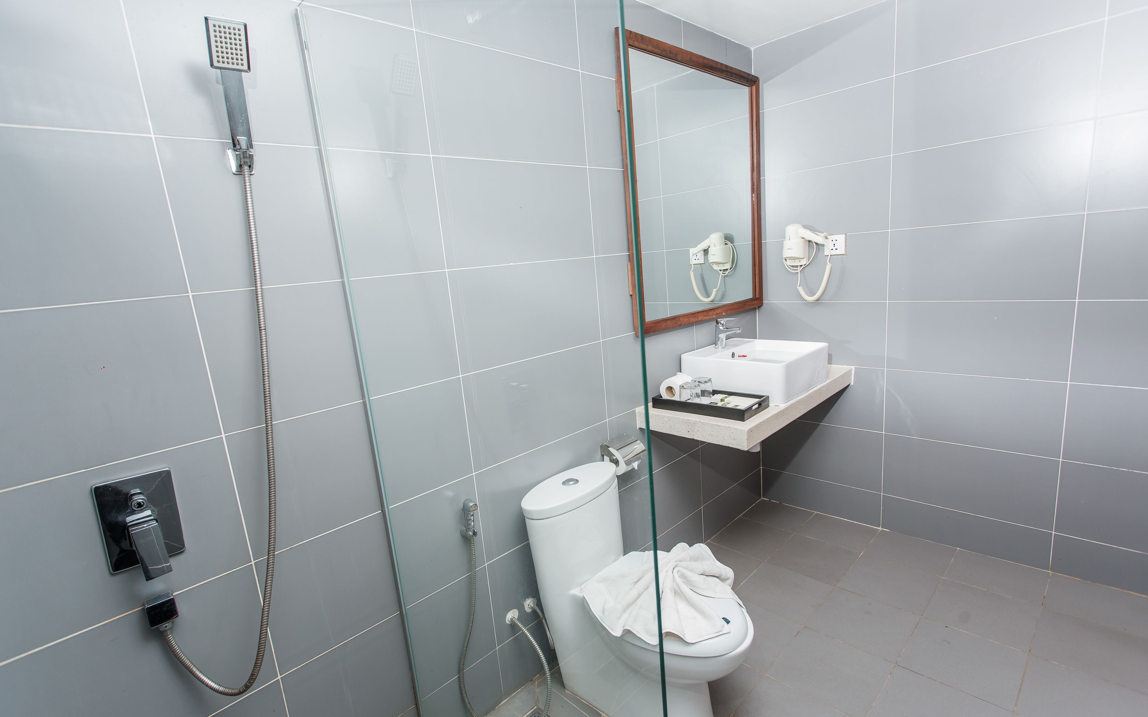 Un baño con cabina de ducha de vidrio, un inodoro blanco, un lavamanos y un espejo.