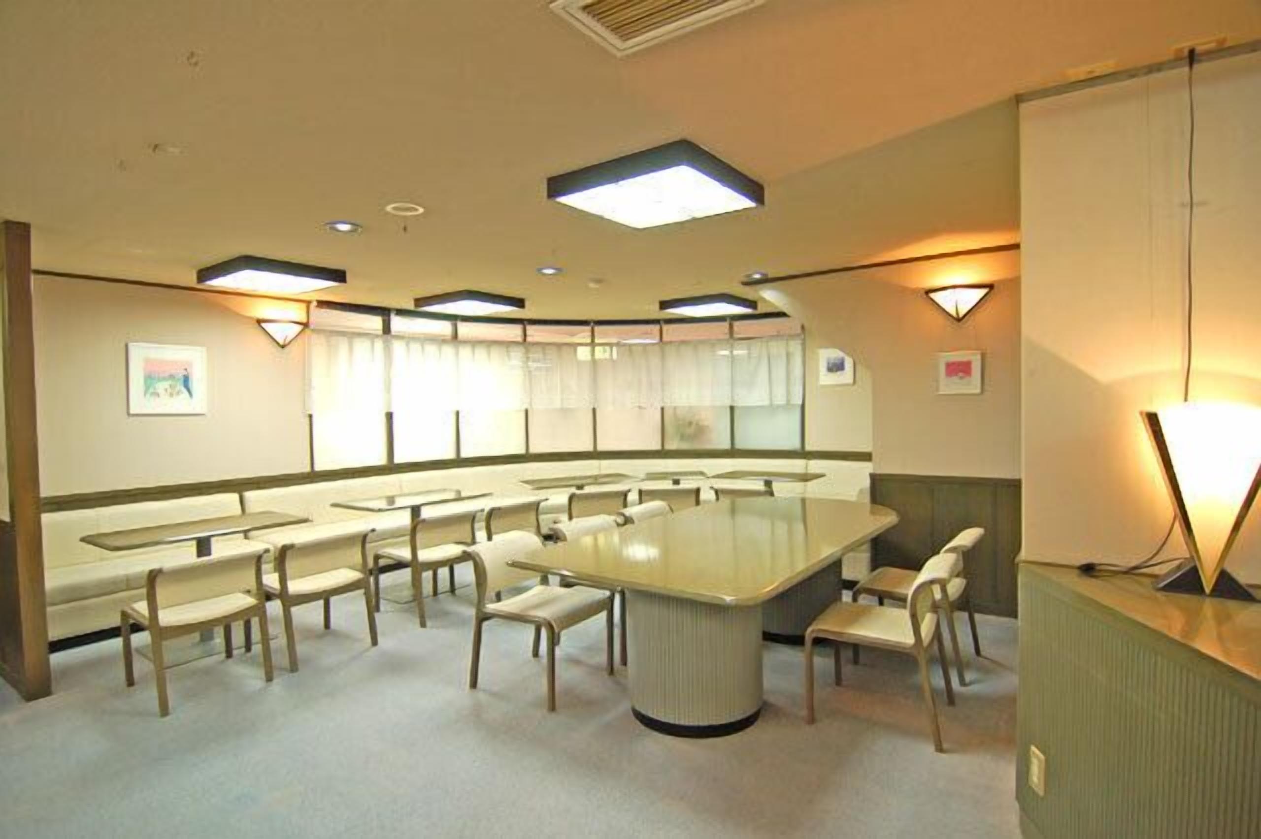 A conference room with a large oval table, multiple chairs, and recessed ceiling lights.