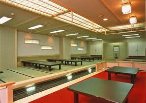 Um quarto com esteiras de tatame, mesas baixas e portas deslizantes tradicionais japonesas.
