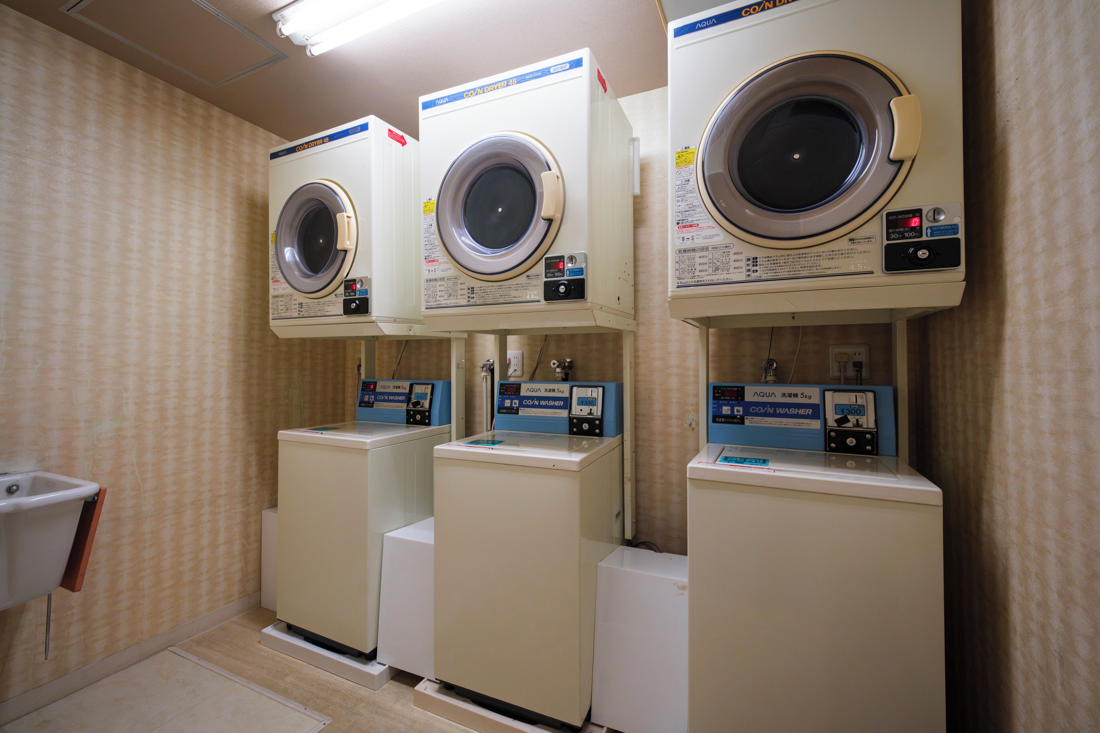 Un cuarto de lavandería con tres lavadoras apiladas y una secadora.