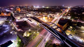 An aerial view of a cityscape at night with illuminated buildings, roads, and a bridge.