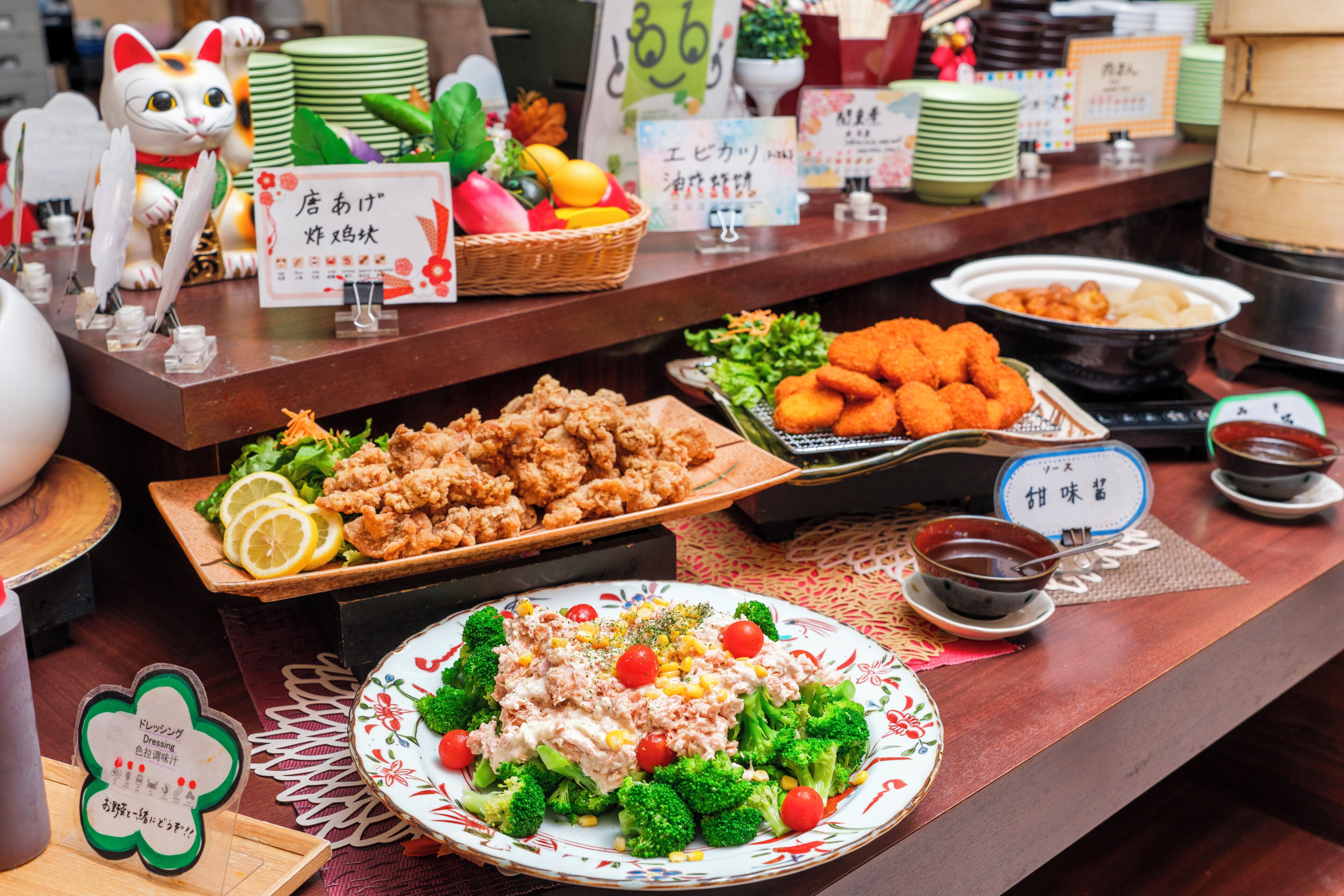 A buffet table with various dishes, including fried chicken, salad, and a bowl of soup.