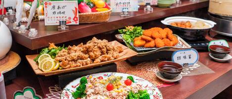 A buffet table with various dishes, including fried chicken, salad, and a bowl of soup.
