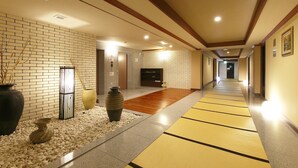 A hallway with a brick wall, a wooden floor, and a tatami mat path.