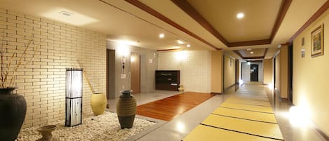 A hallway with a brick wall, a wooden floor, and a tatami mat path.