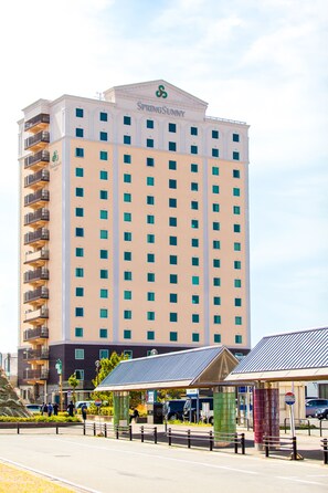 Um hotel alto com um átrio central, várias varandas e entrada coberta.