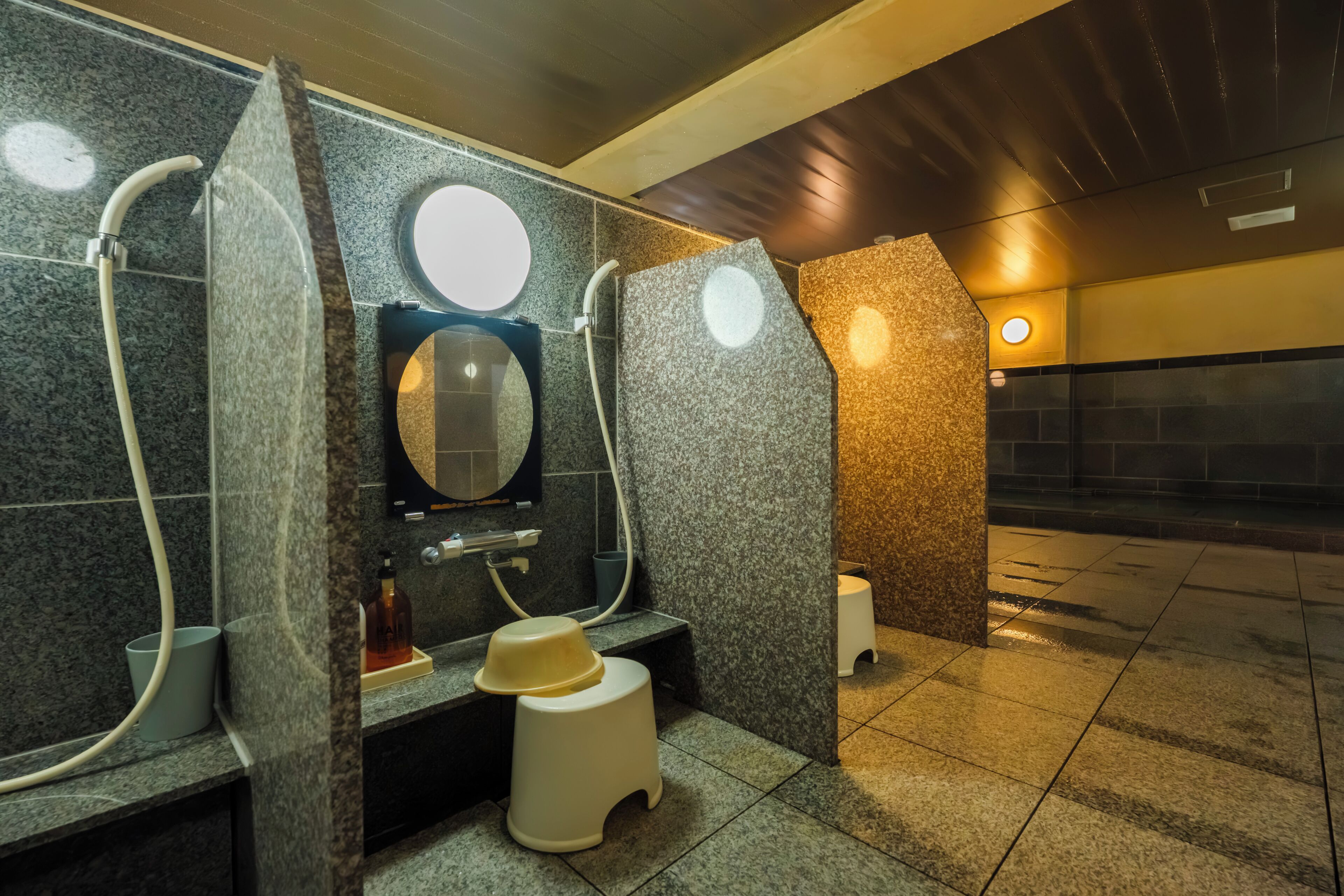 A modern bathroom with granite walls, a mirror, a toilet, and a sink.