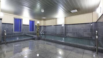 A public indoor swimming pool with tiled walls, a metal ceiling, and blue doors.