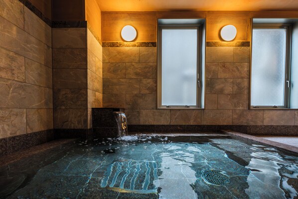 A spa room with a hot tub, two frosted glass doors, and a wall-mounted light fixture.