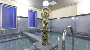 A public bathroom with a statue, blue doors, and a tiled floor.