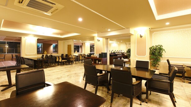 Um restaurante espaçoso com várias mesas e cadeiras, um grande vaso de planta e um design de teto moderno.