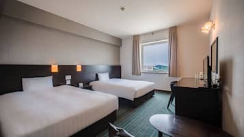 A hotel room with two beds, a desk, a chair, a window with a view, and a bathroom.