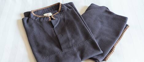 A neatly folded piece of dark fabric with a visible tag on it, placed on a white wooden surface.