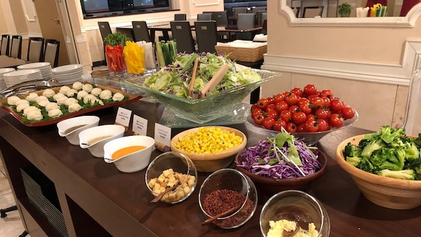 A buffet with various food items including salads, vegetables, and dips.