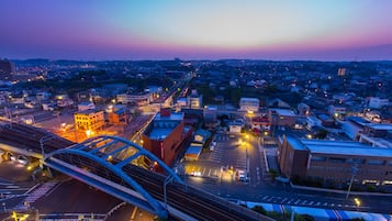 Un paisaje urbano al anochecer con un puente destacado y vías de tren.