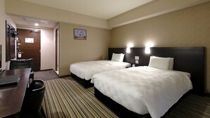 A hotel room with two beds, a desk, and a chair.