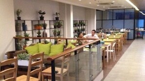 A modern indoor space with a long counter and seating area, featuring glass railings and wooden chairs. - Sare Hotel (Jakarta)