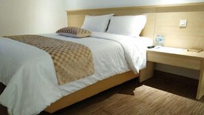 A hotel room with a bed, bedside table, and a wooden headboard. - Sare Hotel (Jakarta)
