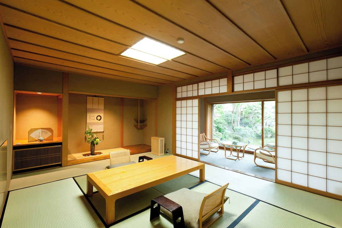 Ein traditioneller japanischer Raum mit Tatami-Bodenbelag, einem niedrigen Holztisch und gleitenden Shoji-Schiebetüren.