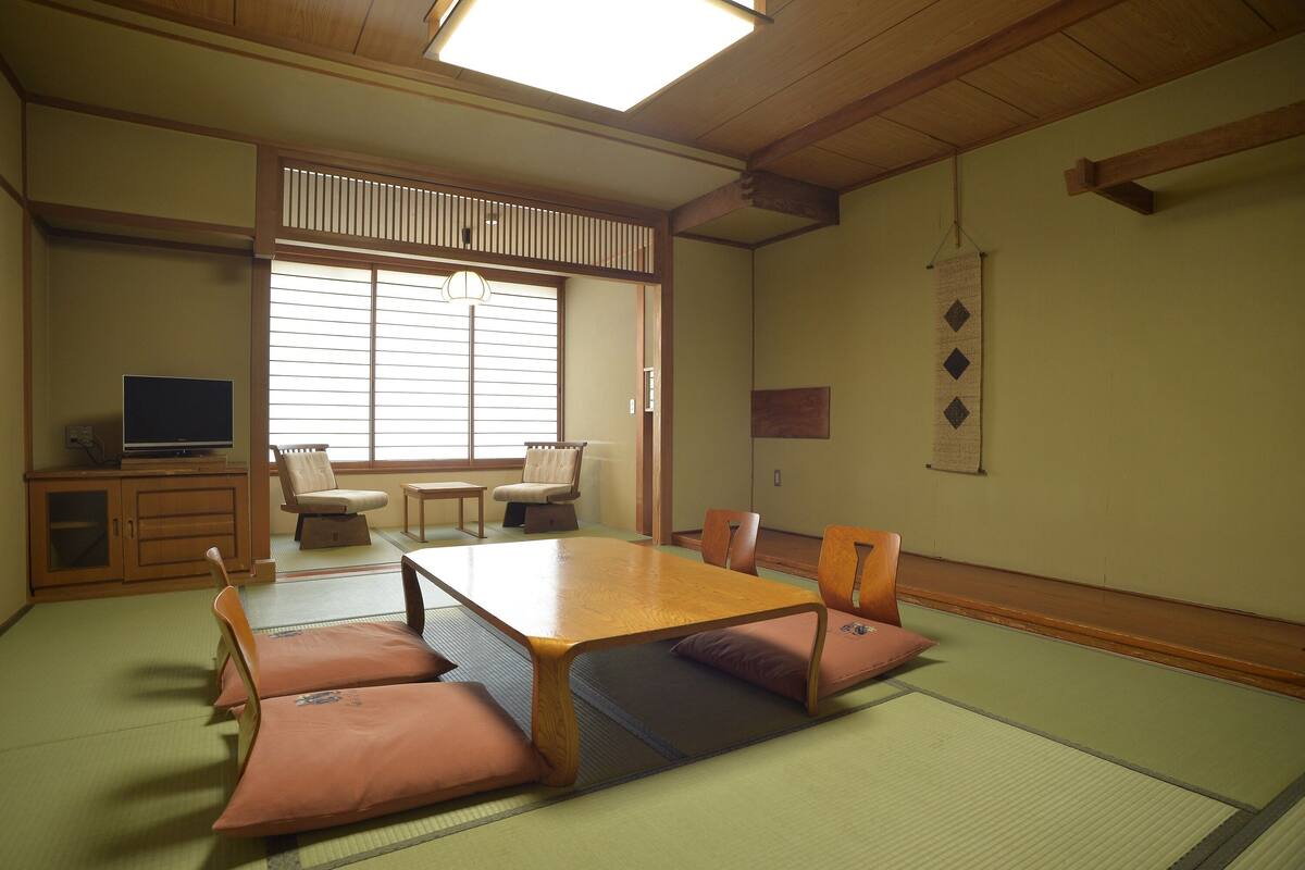 A traditional Japanese room with tatami flooring, a low wooden table, and tatami mats.