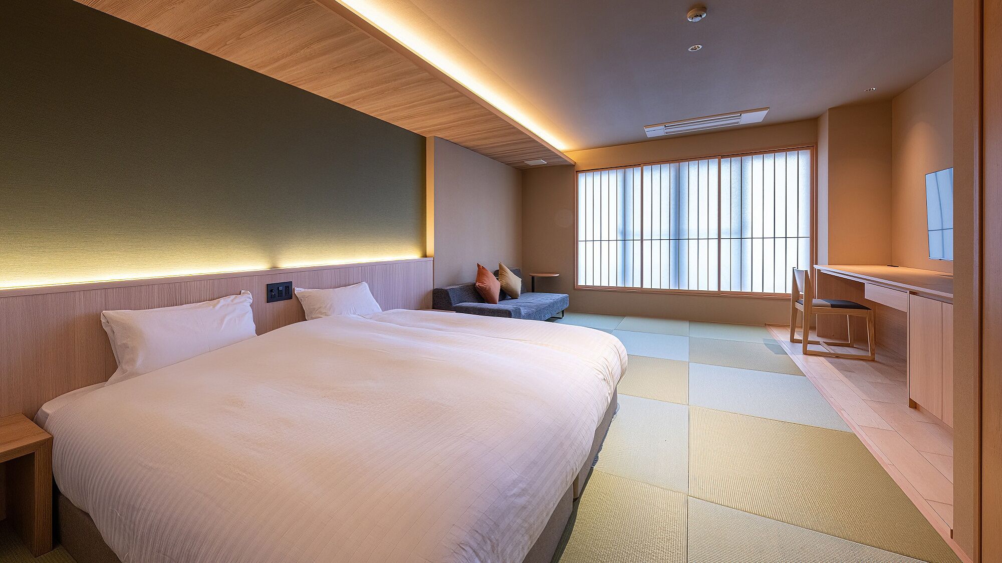 A hotel room with a large bed, a desk, and a view of the outside.