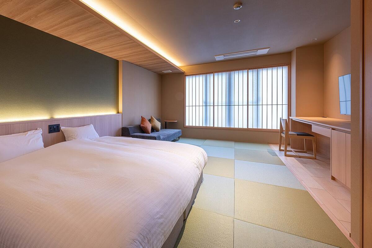 A hotel room with a large bed, a desk, and a view of the outside.