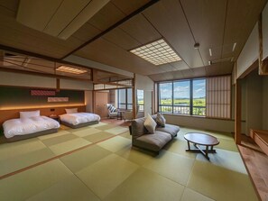 Una tradizionale stanza in stile giapponese con pavimento in tatami, due letti, un divano e un piccolo tavolo.
