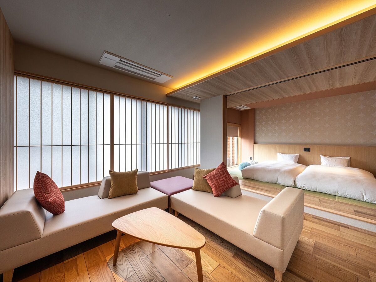A hotel room with a sofa set, a small table, and a bed with a headboard.