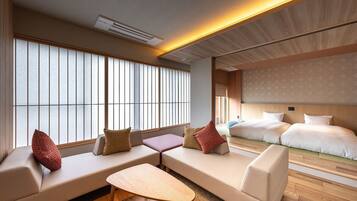 A hotel room with a sofa set, a small table, and a bed with a headboard.