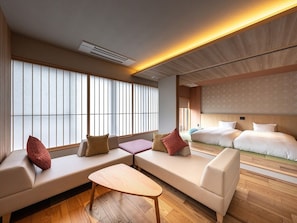 A hotel room with a sofa set, a small table, and a bed with a headboard. - Taisenkaku (Asakura)